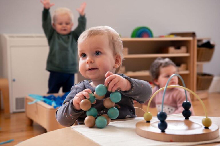 Baby Playing with Wooden Toys and Messy Play in the Background