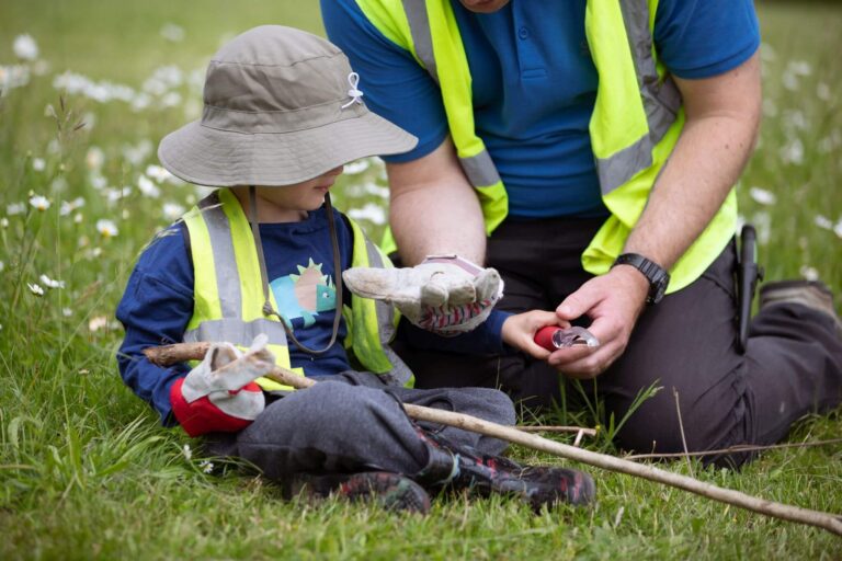 Nursery Nurse Teaching a Boy to Shave a Branch Outdoors
