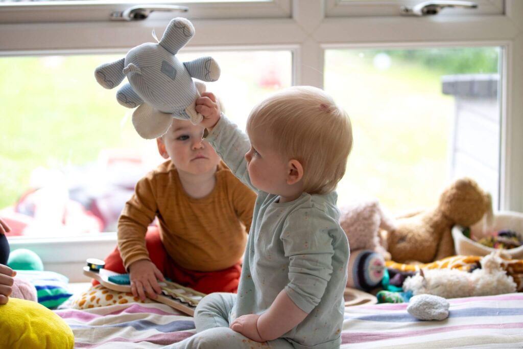 A toddler holding a teddy bear toy, engaging in comforting and imaginative play.