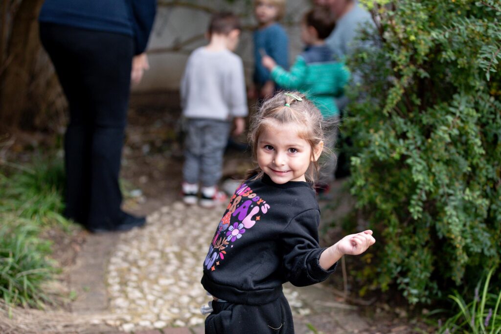 Smiling child in garden path with friends.