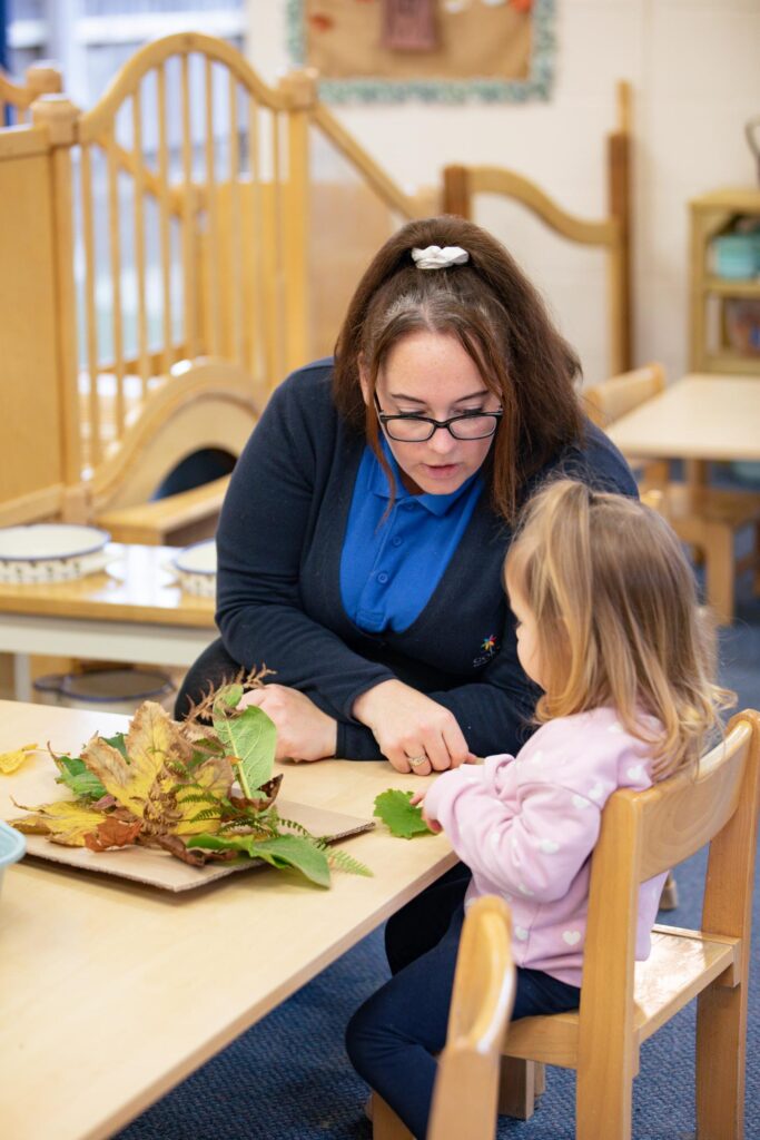 Teacher helping child with nature project.